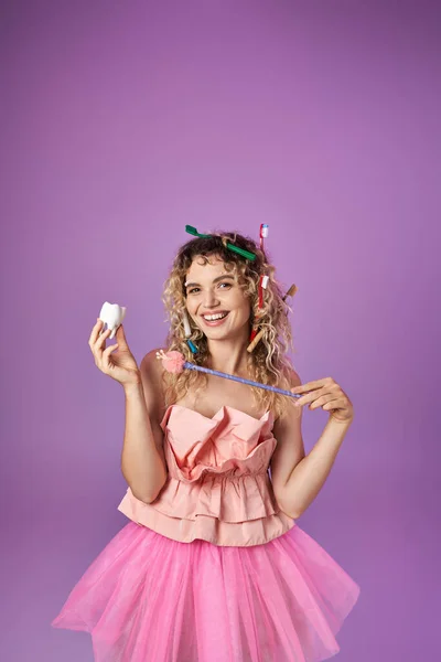 Счастливая зубная фея с зубными щётками в волосах наложила заклинание на молочный зуб своей волшебной палочкой — стоковое фото