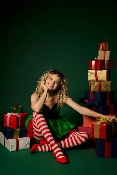Felice anno nuovo elfo seduto con le gambe incrociate circondato da regali e sorridente alla fotocamera — Foto stock