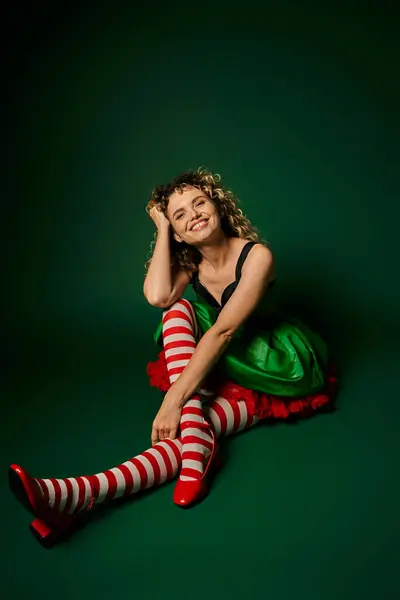 Mujer feliz en vestido festivo con medias a rayas sonriendo a la cámara, concepto de año nuevo elfo - foto de stock