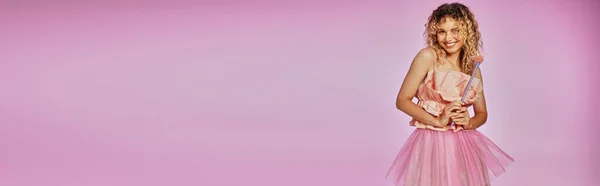 Belle femme en tenue rose tenant baguette magique sur fond rose, concept de fée dentaire, bannière — Photo de stock