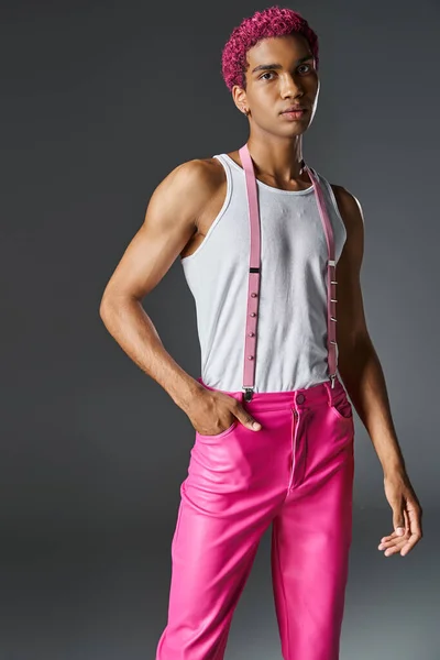 Rosa peludo jovem modelo masculino posando no fundo cinza com uma mão no bolso, moda e estilo — Fotografia de Stock