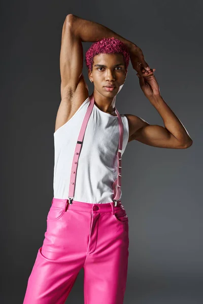 Stylischer Mann in pinkfarbener Hose mit Hosenträgern, Hände hinter dem Kopf und Blick auf Kamera, Mode und Stil — Stockfoto