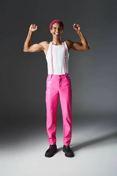Грайлива молода чоловіча модель з рожевим волоссям, що показує м'язи і посміхається на камеру, моду і стиль — стокове фото