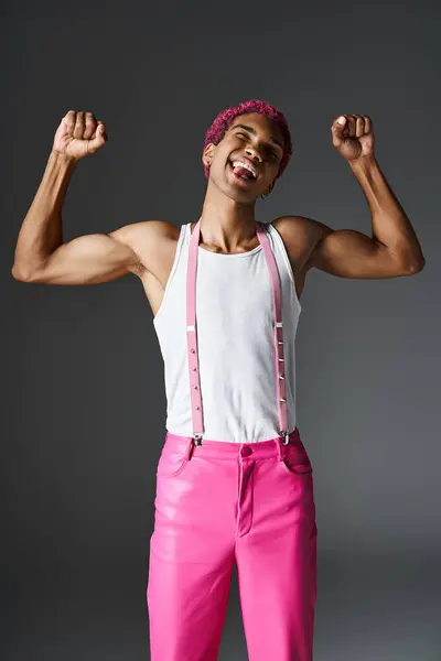 Hombre juguetón y elegante con el pelo rosa mostrando los músculos y sobresaliendo lengua, moda y estilo - foto de stock