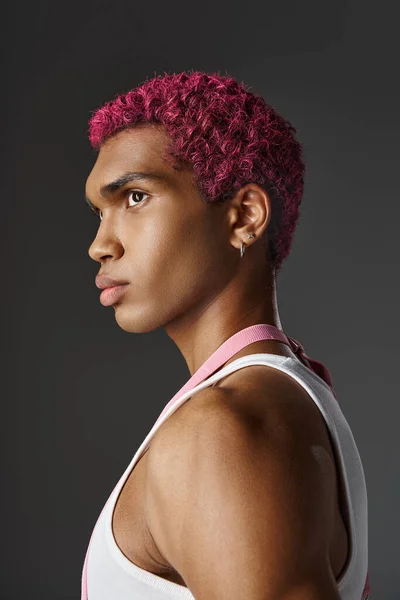 Portrait de jeune homme beau aux cheveux roses et boucles d'oreilles posant de profil, de mode et de style — Photo de stock