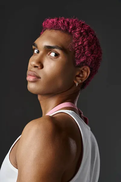 Porträt eines gutaussehenden jungen Mannes mit rosa Haaren, der vor grauem Hintergrund in die Kamera blickt, Modekonzept — Stockfoto