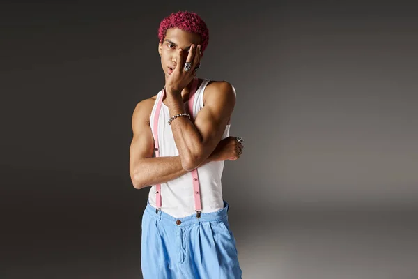 Voguish pink haired man posing with slightly crossed arms on gray backdrop, fashion concept — Stock Photo