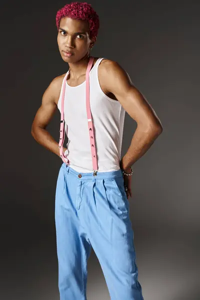 Bel modello maschile posa con le mani dietro la schiena in pantaloni blu su sfondo grigio, moda — Foto stock