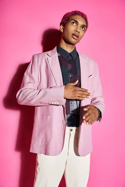 Gut aussehender Mann, der sich unnatürlich verhält wie eine männliche Puppe mit rosa Blazer auf rosa Hintergrund, puppenhaft — Stockfoto
