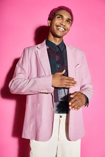 Красивый молодой человек ведет себя неестественно, как кукла улыбается и позирует на розовом фоне — стоковое фото