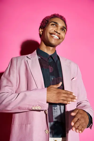 Elegante homem afro-americano gesticulando estranhamente sorrindo e posando em pano de fundo rosa, boneca como — Fotografia de Stock