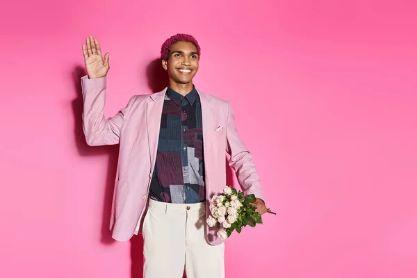 Hombre afroamericano bien parecido sonriendo y actuando como muñeca masculina agitando y sosteniendo ramo de rosas - foto de stock