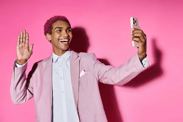 Beau jeune homme posant en agitant anormalement à la caméra de téléphone mobile et souriant joyeusement — Photo de stock