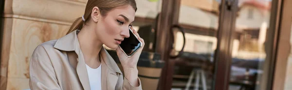 Jeune femme blonde parlant sur smartphone et détournant les yeux tout en travaillant à distance à l'extérieur, bannière — Photo de stock