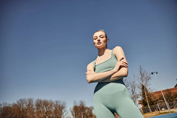 Mulher loira e apta em shorts de ciclismo e top corte posando e olhando para a câmera após o treino — Fotografia de Stock