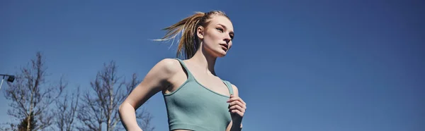 Blonde and fit sportswoman in activewear running outdoors, motivation and sport banner — Stock Photo
