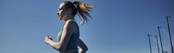 Side view of blonde fit woman in activewear running outdoors, motivation and sport banner — Stock Photo