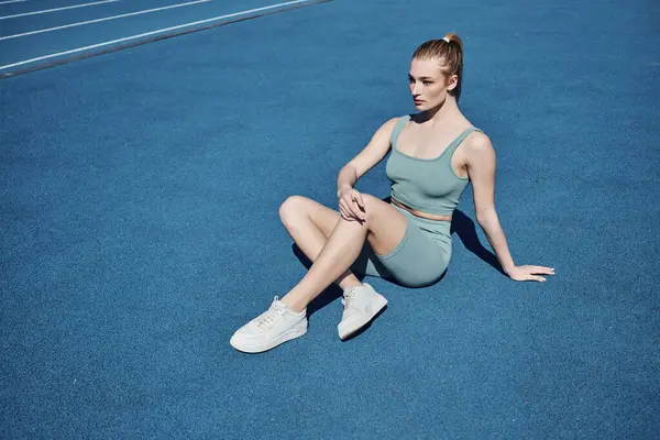 Femme de sport blonde et en forme en vêtements de sport reposant et assis à l'extérieur, la motivation et le sport — Photo de stock