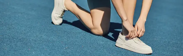 Обрізаний банер, спортсменка в активному одязі зав'язує мережива на кросівках перед бігом у біговій доріжці — стокове фото