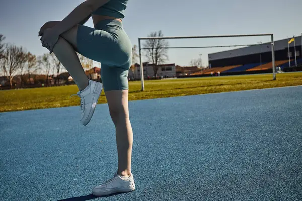 Vista cortada de desportista flexível exercitando em activewear apertado ao ar livre, alongamento perna — Fotografia de Stock