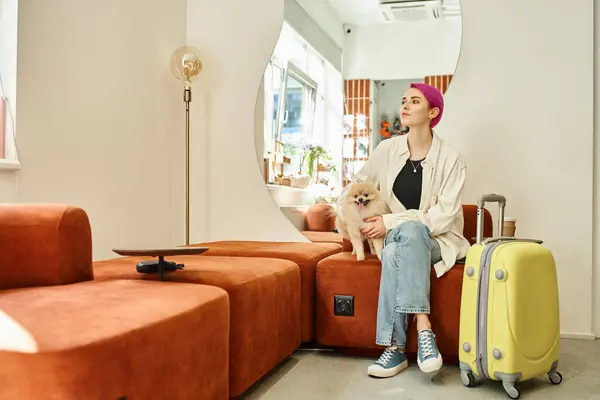 Purple-haired woman with pomeranian spitz and suitcase waiting in lobby of pet hotel — Stock Photo