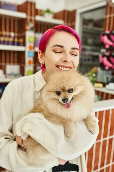 Mulher alegre com olhos fechados abraçando spitz pomeranian adorável no hotel do cão, conceito pet-friendly — Fotografia de Stock