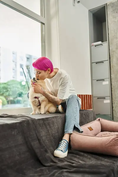 Travailleur de l'hôtel animal de compagnie attentionné avec les cheveux violets embrasser adorable spitz poméranien, chien amour et soins — Photo de stock