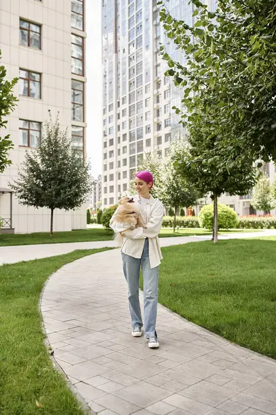 Full length of cheerful woman with pomeranian spitz in hands walking in city, street scene — Stock Photo