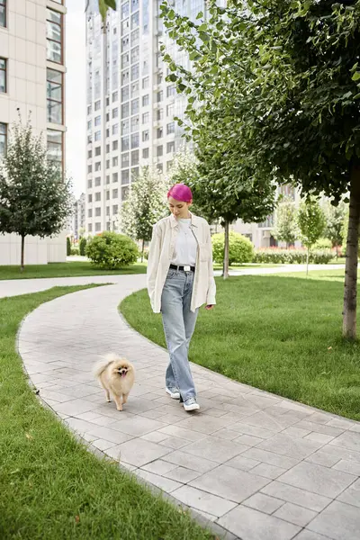 Full length of stylish purple-haired woman walking with pomeranian spitz on urban street, city life — Stock Photo