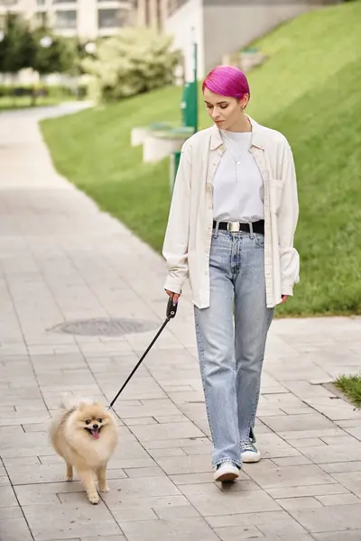 Woman with purple hair walking in city with cute pomeranian spitz on roulette leash, urban life — Stock Photo