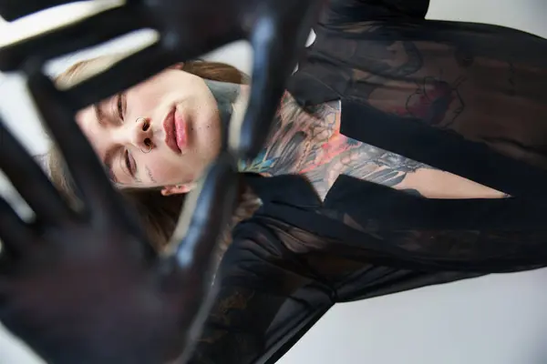 Elegante joven guapo con tatuajes posando con las manos delante de su cara, concepto de moda - foto de stock