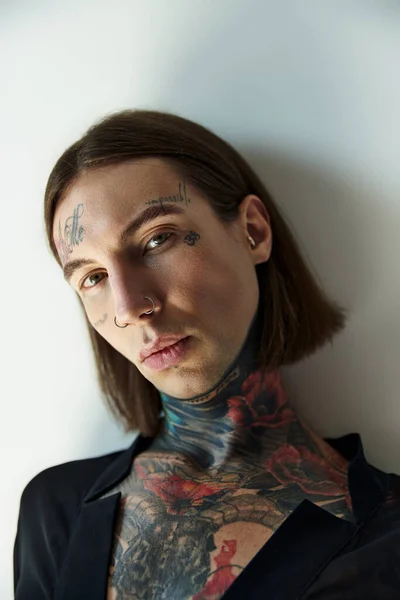 Portrait of sexy alluring male model in transparent black blouse with tattoos looking at camera — Stock Photo
