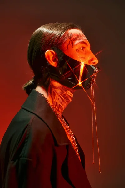 Portrait of young stylish man posing in profile with sparks of light on his laced mask, fashion — Stock Photo