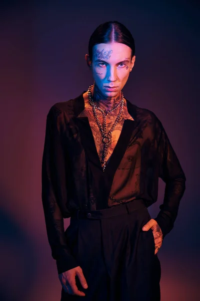 Vertical shot of alluring young man in transparent shirt with tattoos looking at camera, fashion — Stock Photo