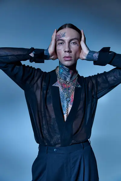 Tiro vertical de homem bonito em camisa transparente com tatuagens tocando sua cabeça, moda — Fotografia de Stock
