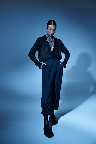 Вертикальный снимок молодой сексуальной мужской модели в черной одежде с руками в карманах, смотрящих вниз, мода — стоковое фото