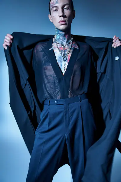 Alluring young man with stylish tattoos posing with hands on his black coat, fashion concept — Stock Photo