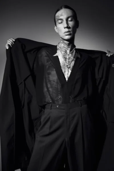 Schwarz-Weiß-Foto eines stylischen Mannes mit Tätowierungen im transparenten Hemd mit Mantel, Modekonzept — Stockfoto