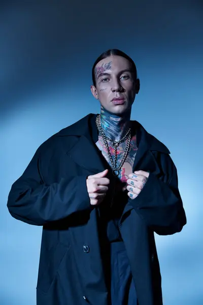 Boa aparência elegante modelo masculino com tatuagens posando com as mãos em seu casaco preto, conceito de moda — Fotografia de Stock
