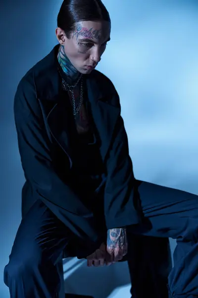 Vertical shot of handsome young man sitting on chair in black attire and looking away, fashion — Stock Photo