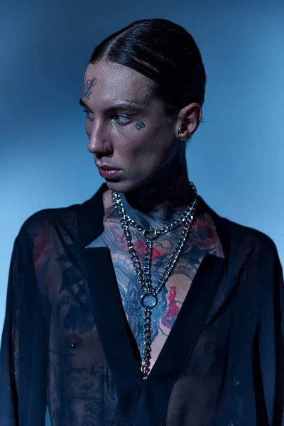 Plan vertical de bel homme élégant avec tatouages et perçage en chemise transparente détournant les yeux — Photo de stock