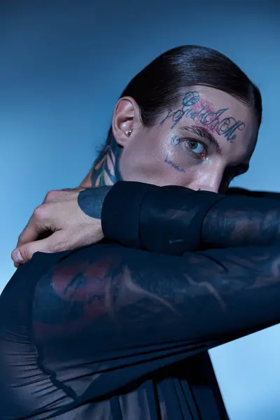 Plan vertical de l'homme séduisant avec des tatouages sur le visage en chemise élégante transparente regardant la caméra — Photo de stock