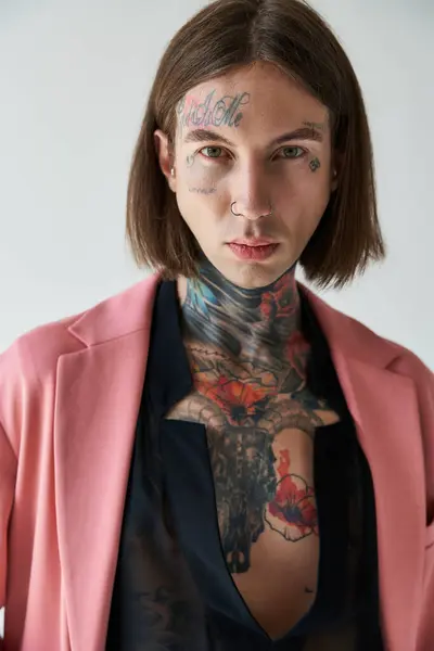 Gut aussehender, verführerischer Mann in stylischem rosa Blazer mit Tätowierungen, der in die Kamera schaut, Modekonzept — Stockfoto
