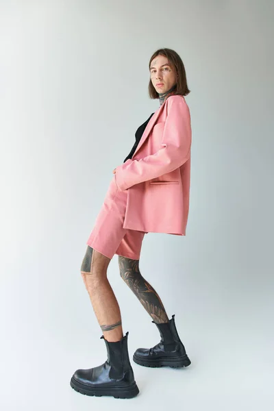 Junges, stylisches männliches Model in rosa Blazer und Shorts, das seinen Körper leicht beugt und in die Kamera schaut — Stockfoto