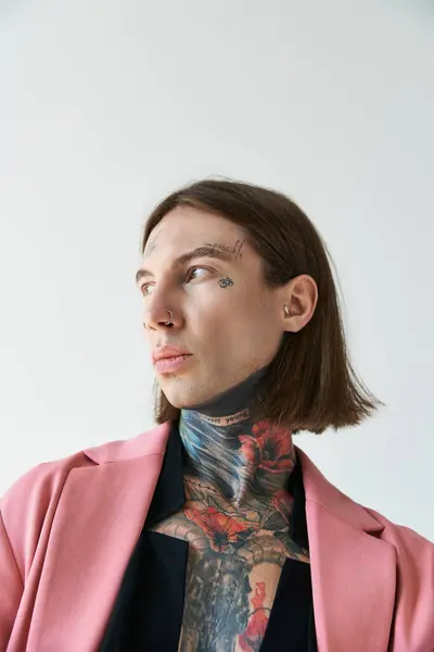 Hombre voguish bien parecido con tatuajes en chaqueta rosa posando y mirando hacia otro lado, concepto de moda - foto de stock
