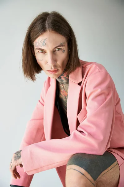 Vertical shot of good looking young man with tattoos looking straight at camera, fashion concept — Stock Photo