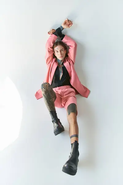 Вид зверху на стильного сексуального чоловіка в рожевому блістері і шортах, що лежать з піднятими руками, концепція моди — стокове фото