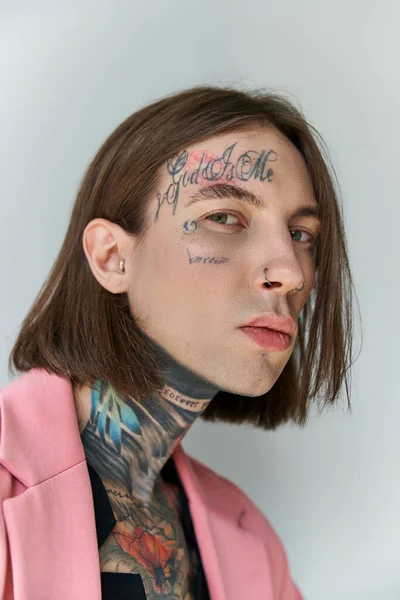 Portrait of handsome young man with stylish tattoos on face looking at camera, fashion concept — Stock Photo