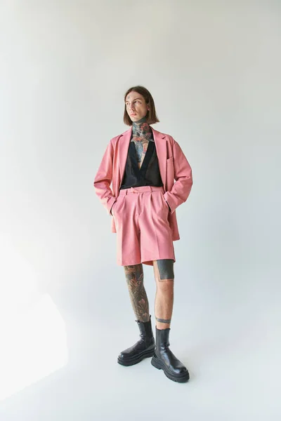 Tiro vertical de joven guapo en chaqueta rosa y pantalones cortos con las manos en los bolsillos, la moda - foto de stock