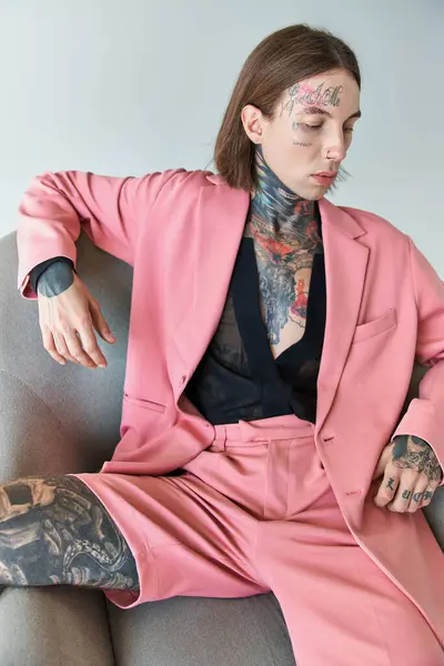 Стильный соблазнительный мужчина с татуировками в розовом пиджаке и шортах, сидящих на стуле, концепция моды — стоковое фото